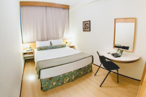 库里提巴阿拉丁酒店的卧室配有1张床、1张桌子和1把椅子
