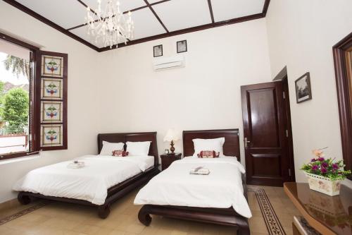 玛琅Huis Van Gustafine Floor 1的配有白色墙壁和吊灯的客房内的两张床