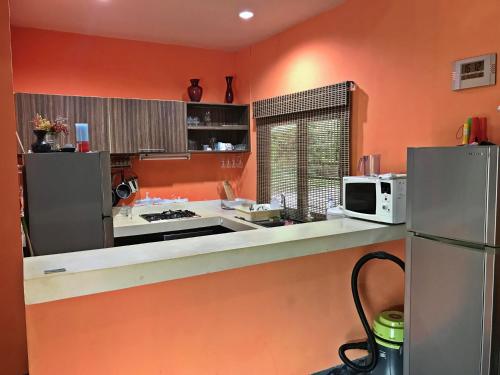 班阁库安Tropical Hillside Villa的厨房设有橙色墙壁和带微波炉的台面。