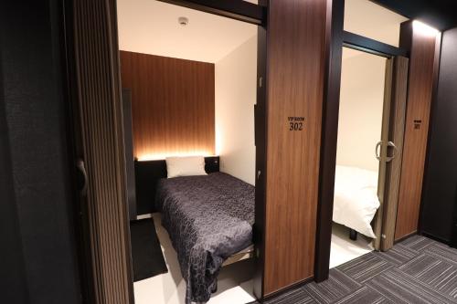船桥市LEO YU Capsule Hotel Nishifunabashi的小房间设有床和镜子