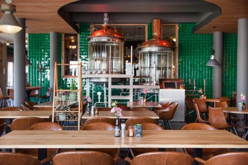 Veendam公园景观酒店的餐厅设有木桌和椅子,拥有绿色的墙壁
