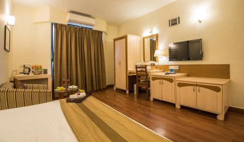 浦那公园中央舒适E套房酒店的酒店客房配有一张床和一张书桌及一台电视