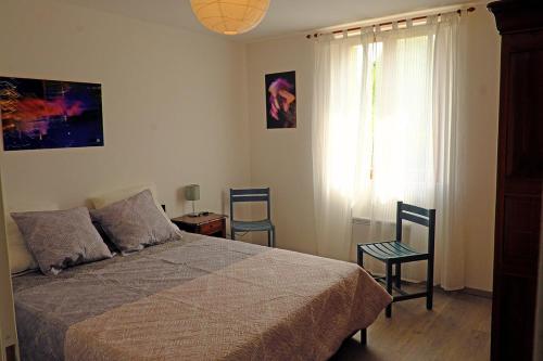 赛尼翁Envies en Lubéron的一间卧室配有一张床、两把椅子和一个窗户