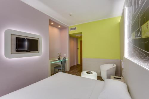 米兰Kleos Hotel Milano的一间设有床铺和墙上电视的房间