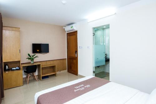海防和芳酒店的一间卧室配有一张床、一张书桌和一台电视。