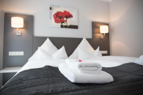 霍耶斯韦达ApartHotel "Am Fließ"的一间卧室配有带毛巾的床