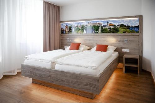库姆巴赫埃尔特酒店的卧室配有一张大床,墙上挂有绘画作品