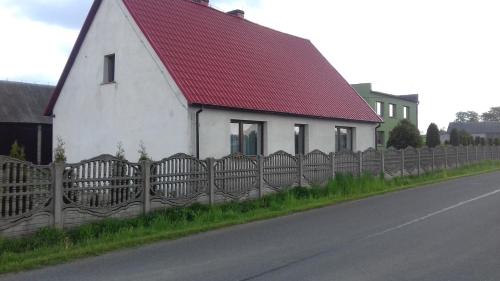 科贝拉古拉Agroturystyka u Pawła i Asi的一间白色房子,有红色屋顶,靠近栅栏