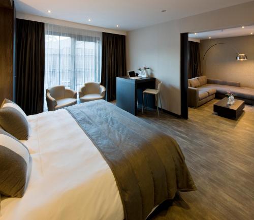 奥斯特坎普Van Der Valk Hotel Brugge Oostkamp的酒店客房设有一张大床和一间客厅。
