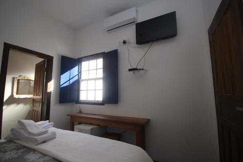 蒂拉登特斯Pousada Sinhá Vilaça的一间卧室设有一张床、一个窗口和一台电视