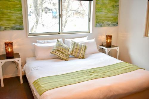 白马村Altitude Apartments Hakuba的一间卧室配有带2个床头柜和2个窗户的床