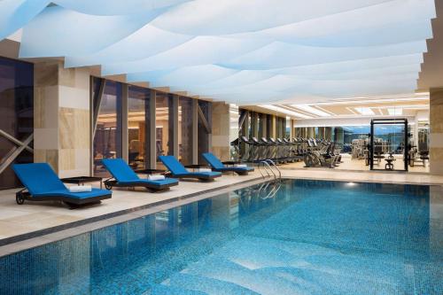 利雅德利雅德奥莱亚凯悦酒店的酒店大堂的游泳池,设有蓝色椅子