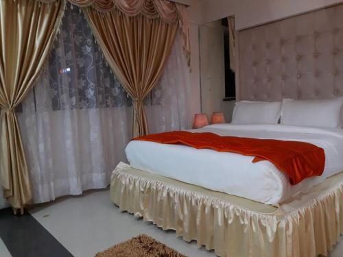 纳威孟买塞特拉克橙旅馆的一间卧室配有一张带红色毯子的大床