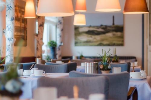 诺德奈Inselhotel Bruns的餐厅配有白色的桌椅和灯光