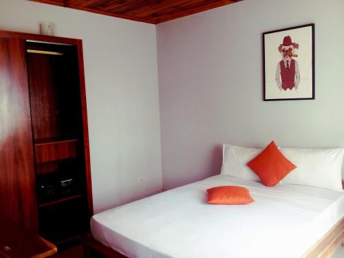 马哈赞加New Park Resort的卧室配有白色床和橙色枕头