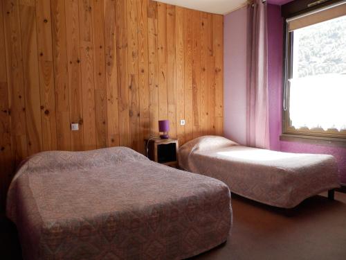 拉尔让蒂埃拉贝塞埃Hotel La Gare的配有窗户和木墙的客房内的两张床