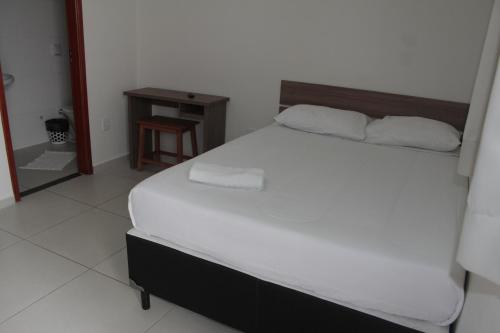 马里利亚Leati's Hotel的卧室配有一张白色的大床和一张桌子