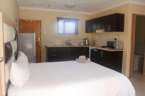 UlundiMbopha Guest House的一间带白色床的卧室和一间厨房