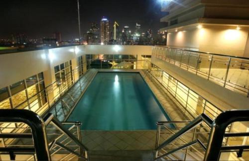 马尼拉Herald Suites Solana的一座游泳池,在晚上在一座建筑的顶部
