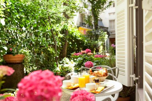 巴黎帕西小村酒店的露台上的桌子上摆放着食物、饮料和鲜花