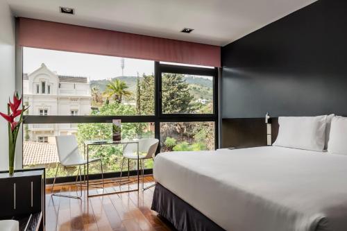 巴塞罗那Ikonik Anglí的一间卧室设有一张大床和一个大窗户