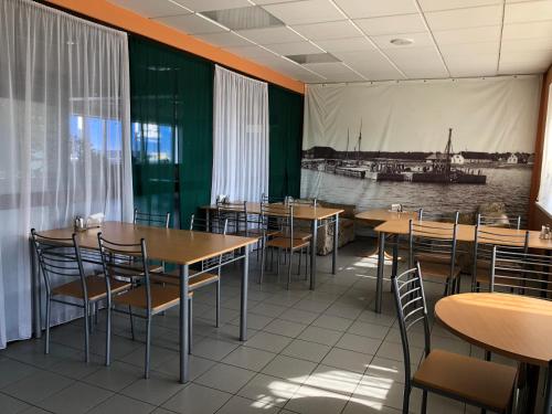 HeltermaaHeltermaa Hostel的一间带桌椅的餐厅,并展示了一张船景