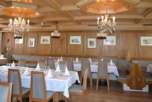 萨伦蒂诺Hotel Alpenblick的用餐室配有白色桌椅和吊灯。
