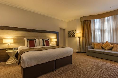 伦敦Thistle London Holborn的酒店客房设有一张大床和一张沙发。
