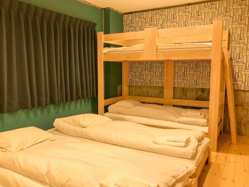 高松绀屋町库库旅馆的带两张双层床的绿色墙壁客房
