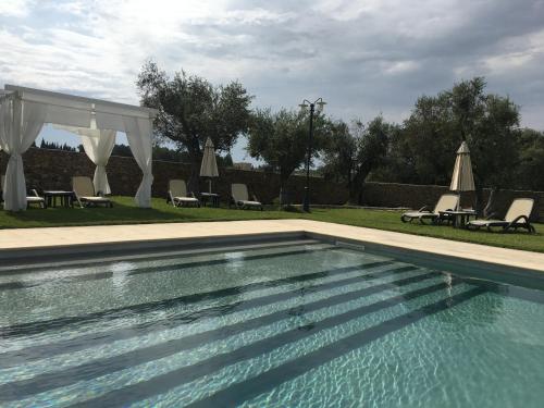 Squinzano马塞里亚圣保罗酒店的庭院内的游泳池,配有椅子和遮阳伞
