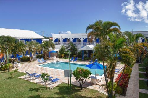 格罗斯岛海湾花园旅馆的一个带游泳池、棕榈树和椅子的度假酒店