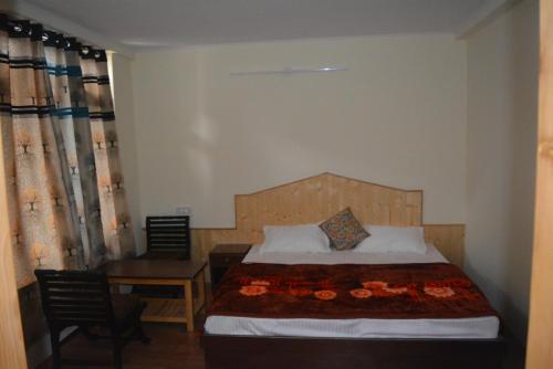 马拉里Himalaya Cottage的卧室配有1张床、1张桌子和1把椅子