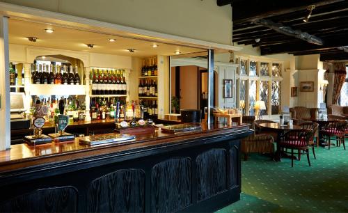 福里斯特罗Roebuck by Greene King Inns的餐厅内的酒吧配有桌椅