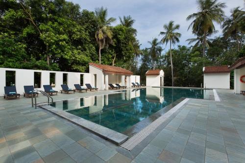 库姆巴科纳姆Mantra Koodam Kumbakonam-CGH Earth的度假村的游泳池,带椅子和树木