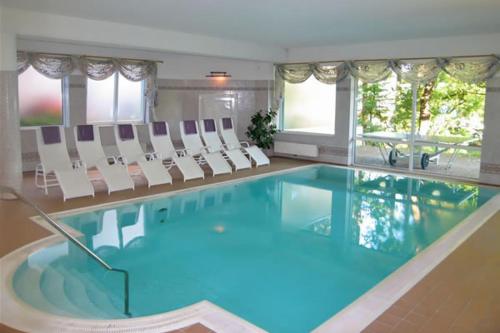 圣卡尼兹比肯霍夫希酒店的一个带白色椅子的大型游泳池和一个游泳池