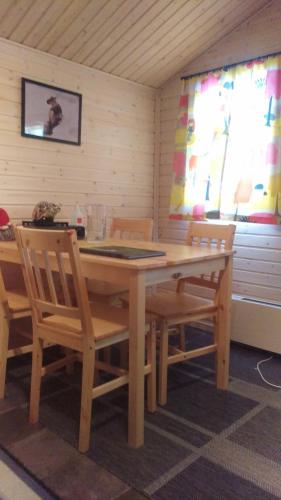 基律纳JVT Cabins的配有2扇窗户的客房内的一张木桌和椅子