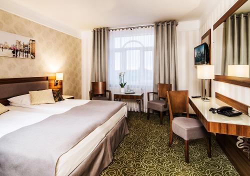 华沙华沙​​机场洛德酒店的配有一张床和一张书桌的酒店客房
