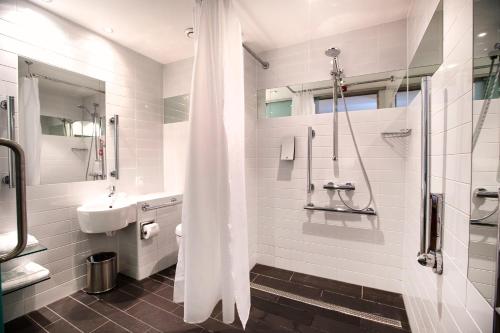 邓迪Sleeperz Hotel Dundee的带淋浴和盥洗盆的白色浴室