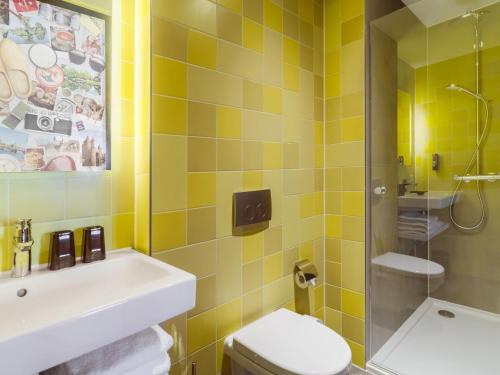 哈莱姆the niu Dairy的浴室设有水槽、卫生间和黄色瓷砖。
