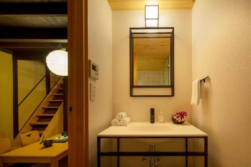 京都熊秀庵町家的一间带水槽和镜子的浴室以及楼梯