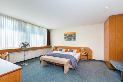 科隆瑟万提斯酒店的一间卧室配有一张床和一张带风扇的书桌