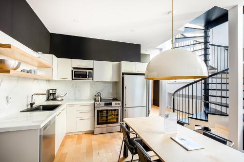 魁北克市Les Lofts St-Pierre - Par Les Lofts Vieux-Québec的厨房配有白色橱柜、桌子和楼梯。