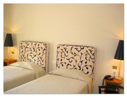 帕杜拉Hotel Certosa的一间卧室配有两张床、电话和灯具。