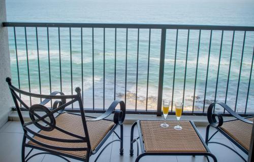 德班1104 The Bermudas - by Stay in Umhlanga的阳台上配有两把椅子和一张桌子,享有海景