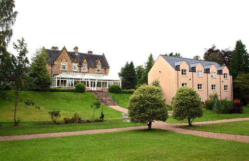 因弗内斯Inverness Lochardil House的一座大房子,位于山丘上,前面有树木