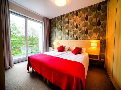 米兹多洛杰金郁金香扎科帕公寓酒店的一间卧室配有一张带红色毯子的大床