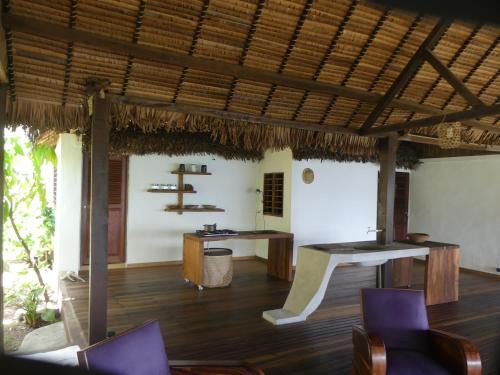 Nosy KombaPicalélouba的一间铺有木地板的用餐室和茅草屋顶