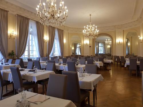 芒通帕拉迪索酒店的餐厅设有白色的桌椅和吊灯。