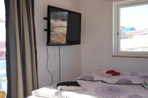 Oqaatsut奥吉萨特/罗德贝住宿加早餐旅馆的卧室配有一张床铺,墙上配有电视