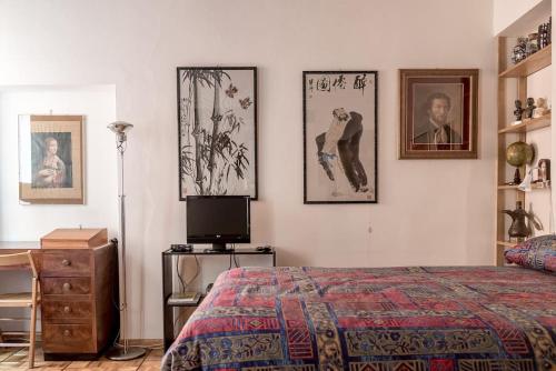 帕尔马Studio Borgo Colonne的卧室配有一张床,墙上挂有图片